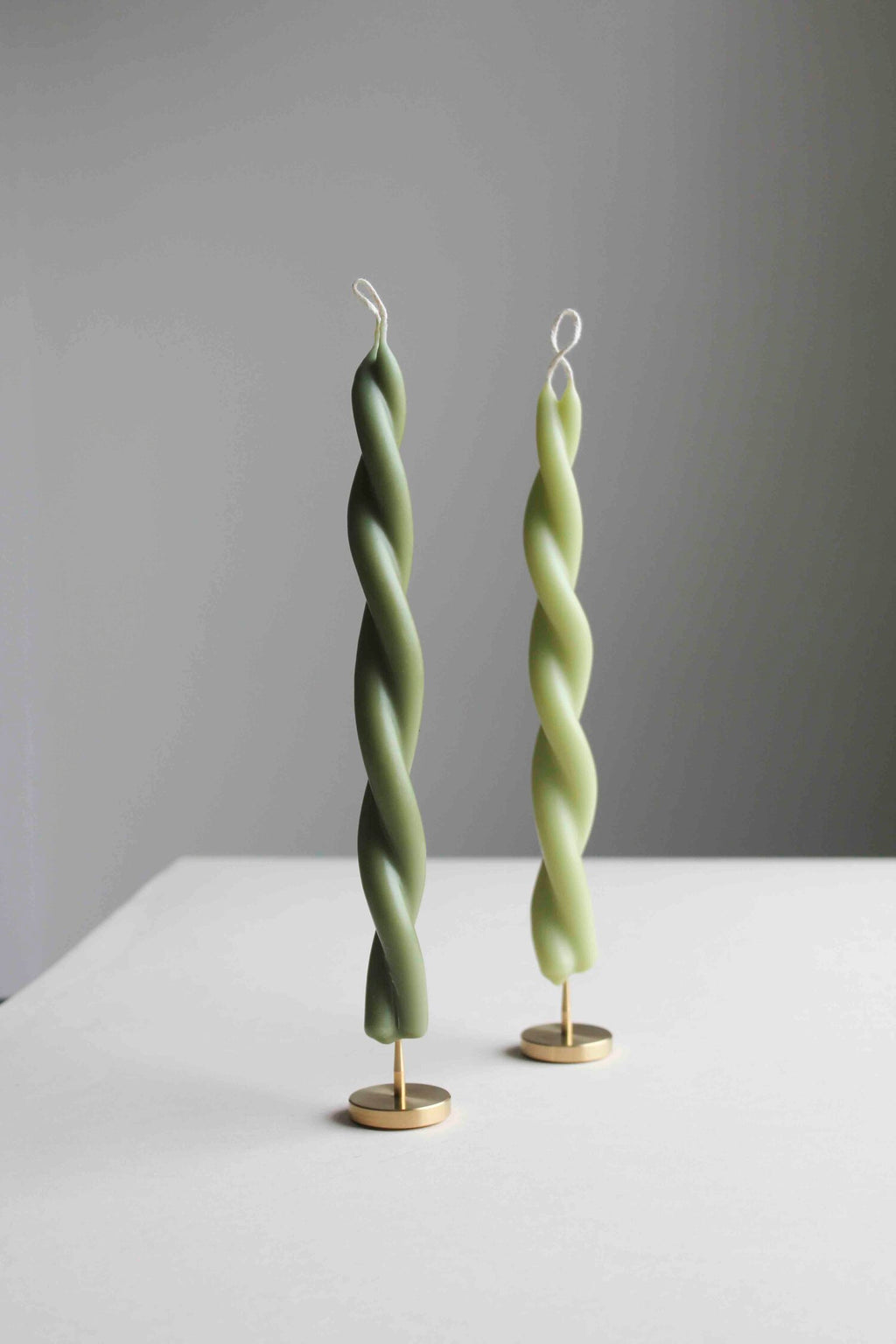 two twisted candles on two solid brass spike candle holders