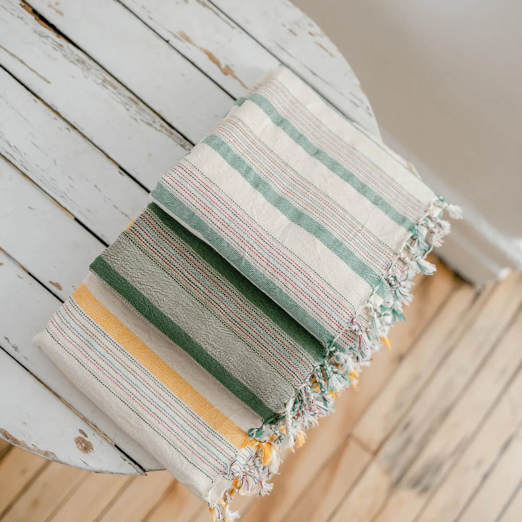 Striped fabric with green, yellow, and white colors draped over a wooden surface.