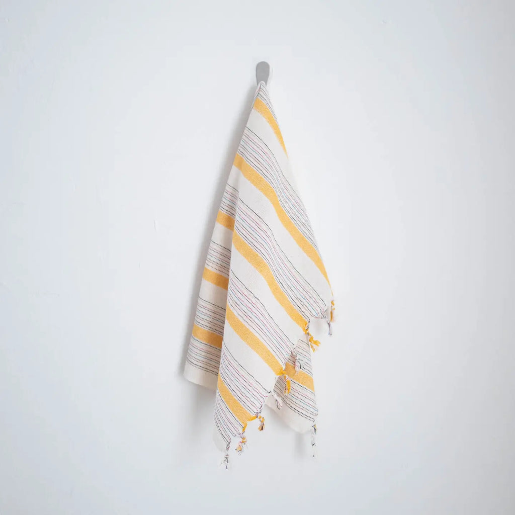 Striped towel with yellow and gray pattern hanging on a white wall