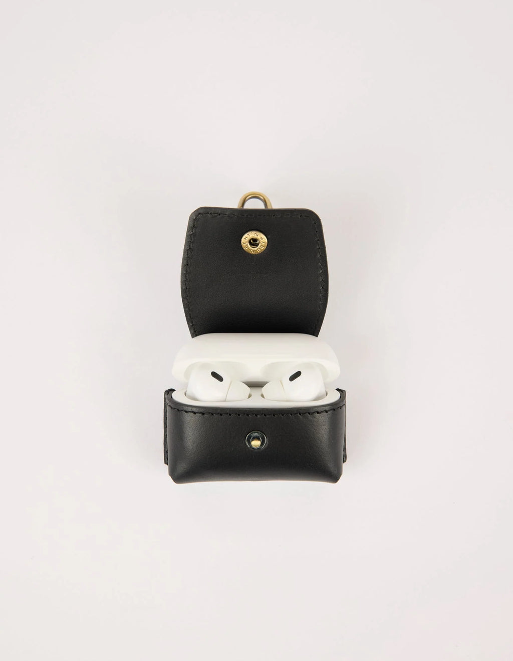 Black leather case with gold accents containing white earbuds on a light gray background