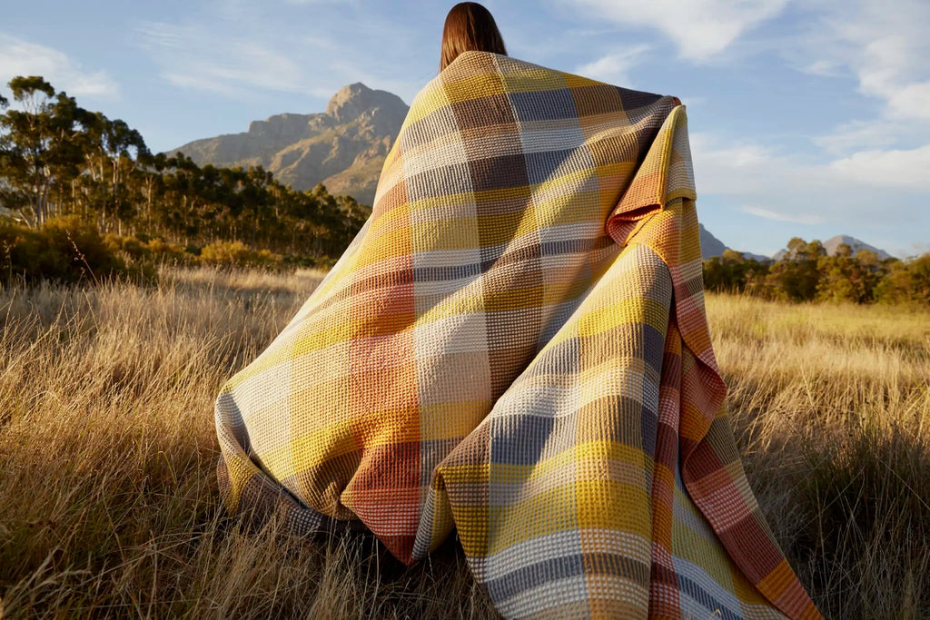 A person using the Mungo blanket to stay warm outside.