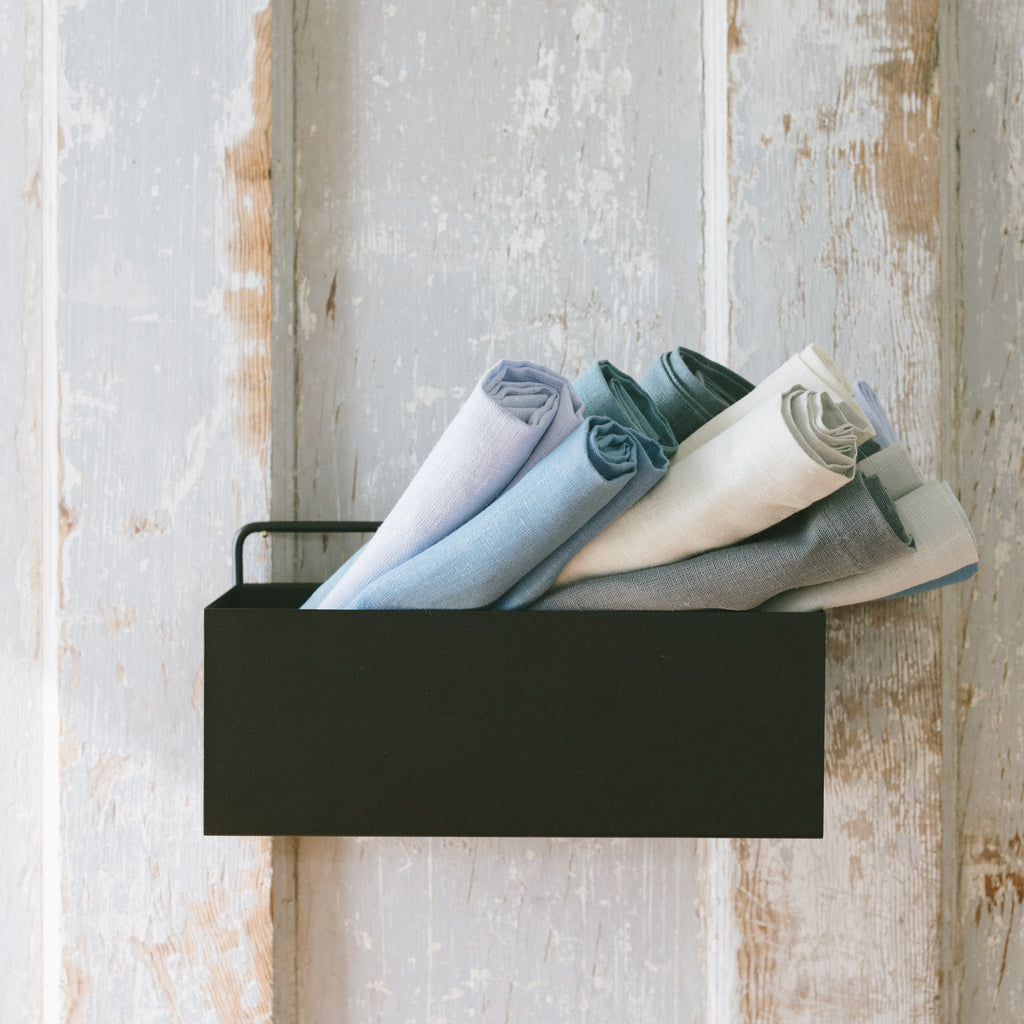 A black powder-coated planter wall box being repurposed for napkins.