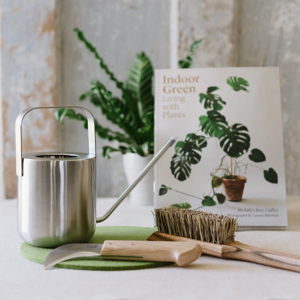 A carbon steel curved knife sitting alongside a variety of gardening tools.