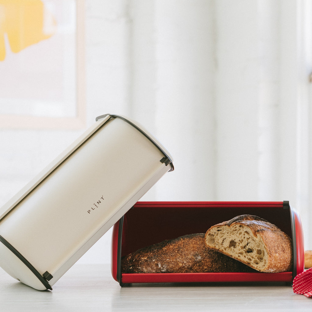 Two Retro Scandinavian-Style Metal Breadboxes, one closed, and one full of fresh-baked bread.