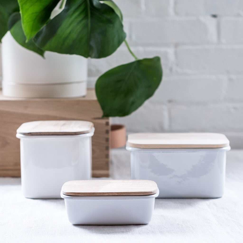 three different sizes of enamel storage containers with acacia wood lids