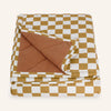 Folded checkered pet blanket with brown and white pattern on a white background