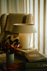 Lamp on a table with books and decorative items in a cozy room setting.