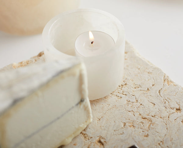 White candle in a holder on a marble surface