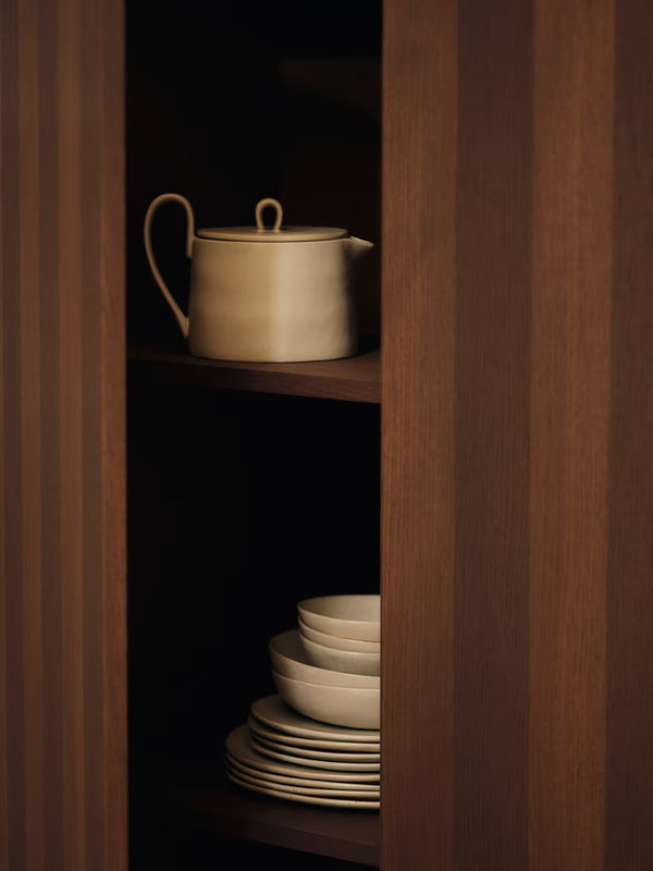Ceramic pots and plates on a wooden shelf with a dark background