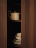Ceramic pots and plates on a wooden shelf with a dark background