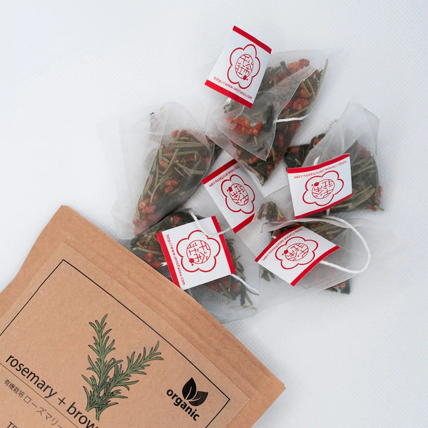 Tea bags with rosemary and brown label on a white background