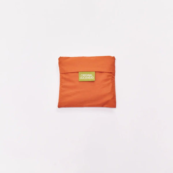An orange compact pouch with a small green label reading 'ORIGINAL DUCKHEAD' in the center, set against a plain white background.