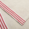 Close-up of a woven textile with a natural beige linen-like base and a striped border featuring red and white stripes.