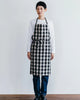 Person wearing a black and white checkered apron against a plain background