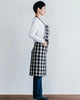 Person wearing a black and white checkered apron against a plain background
