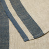 Close-up of a woven textile with a beige herringbone pattern and two vertical navy blue stripes.
