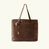 Brown leather tote bag with a gold clasp on a white background
