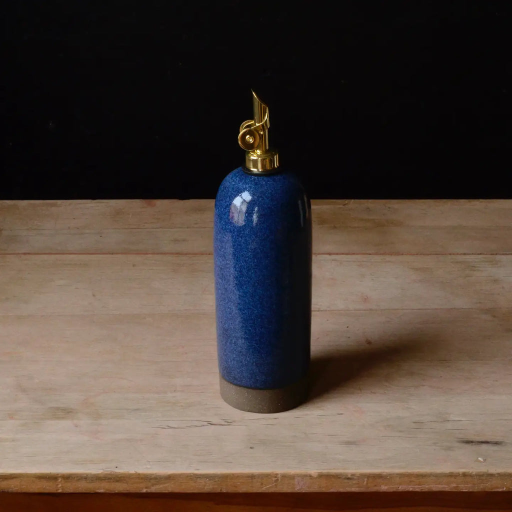 Blue ceramic oil bottle with gold cap on a wooden surface