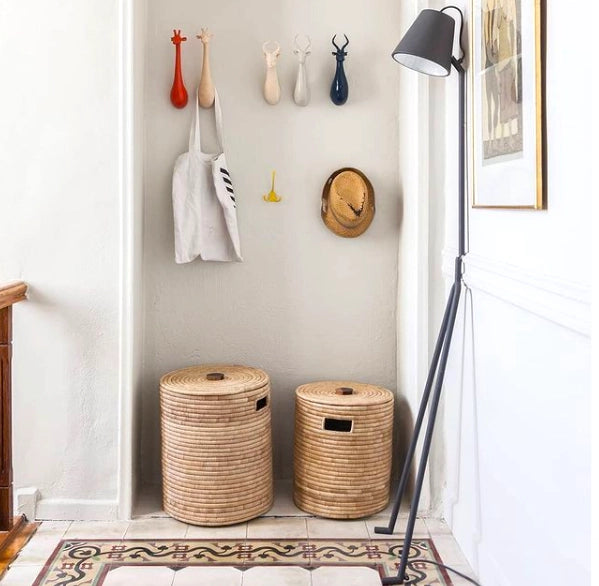 Two woven laundry baskets in a room with a lamp and wall decorations.