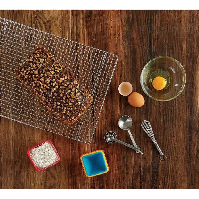 Measuring spoons in stainless steel on a wooden table with bread, eggs and flour.