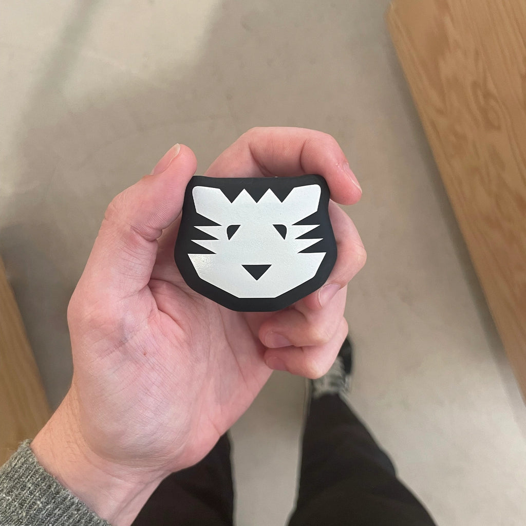 Hand holding a black and white tiger patch against a neutral background