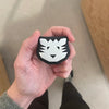 Hand holding a black and white tiger patch against a neutral background
