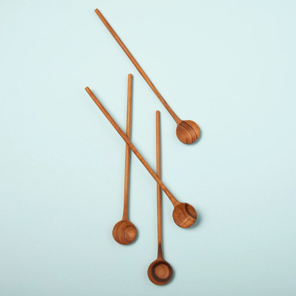 Four wooden spoon stirrers made from teak wood. Laying on a flat blue surface