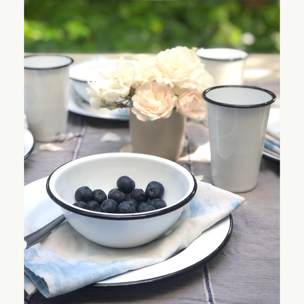 Bowl of blueberries on a table setting with flowers and cups.