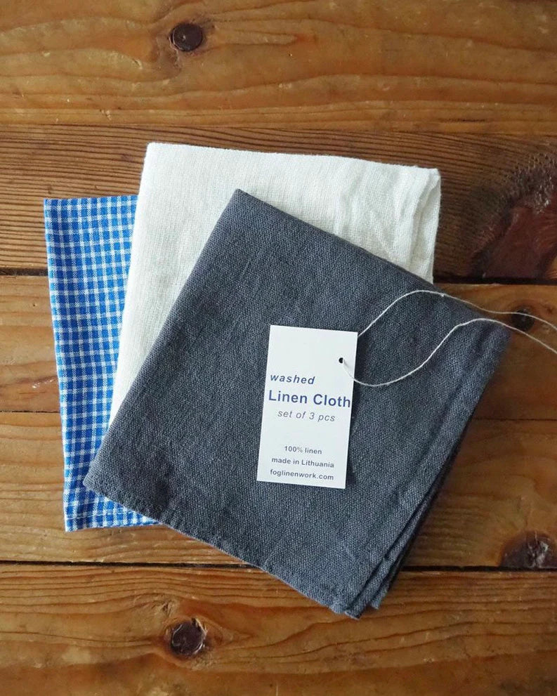 Set of three linen cloths on a wooden surface with a visible tag.
