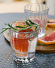 Clear glass with grapefruit and rosemary on a metal surface