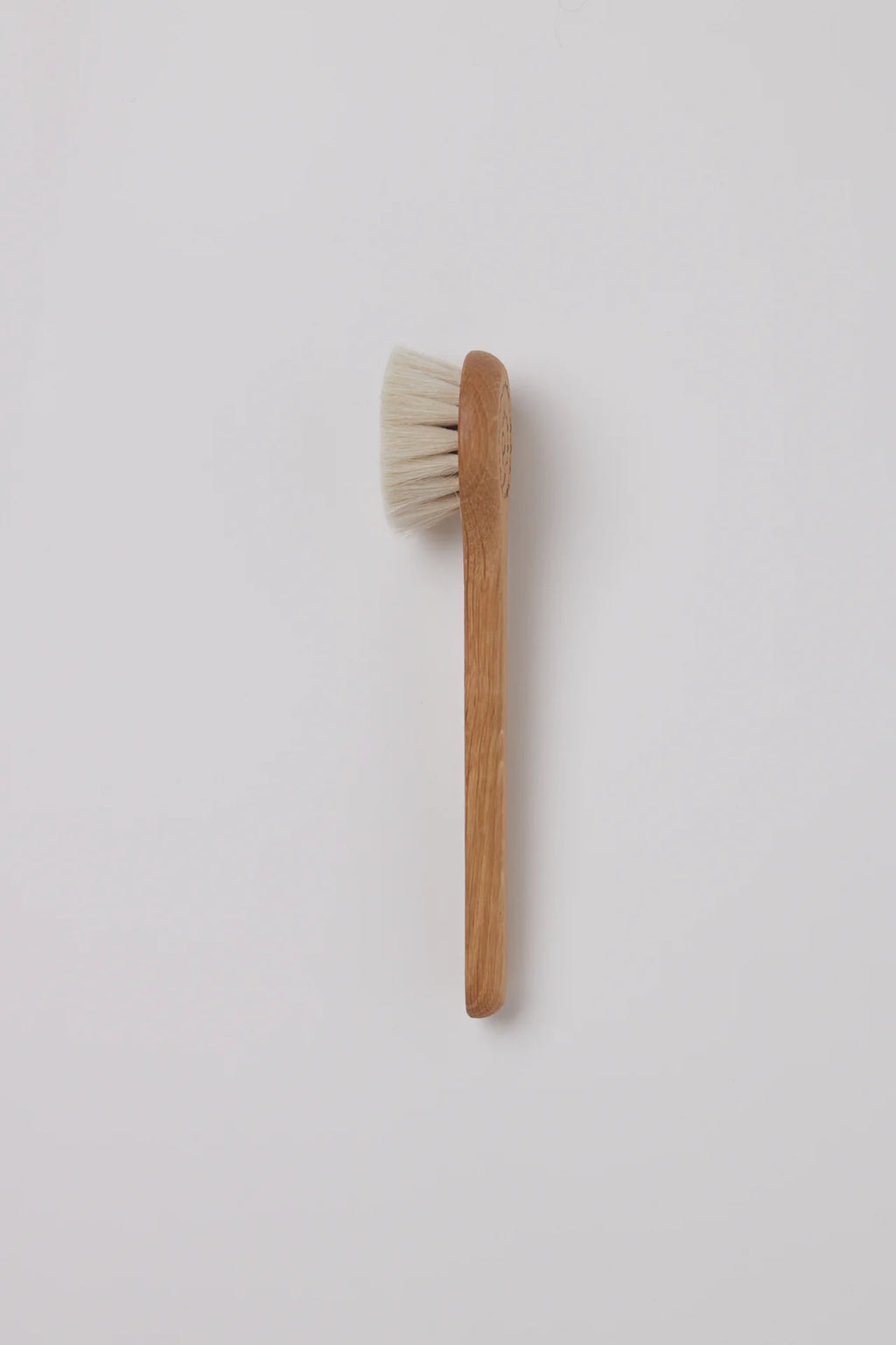 Wooden brush with white bristles on a light gray background