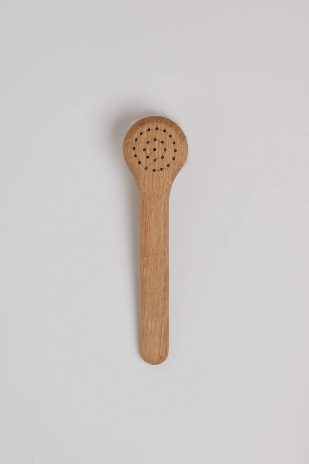 Wooden brush with a perforated design on a light gray background