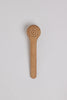 Wooden brush with a perforated design on a light gray background