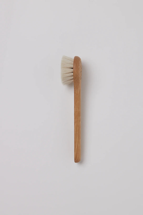 Wooden brush with white bristles on a light gray background