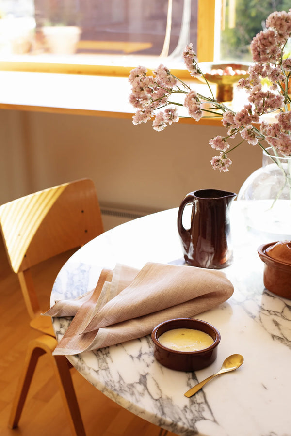 Beautiful table setting with natural light. marble table with a dessert, a folded napkin, flowers.