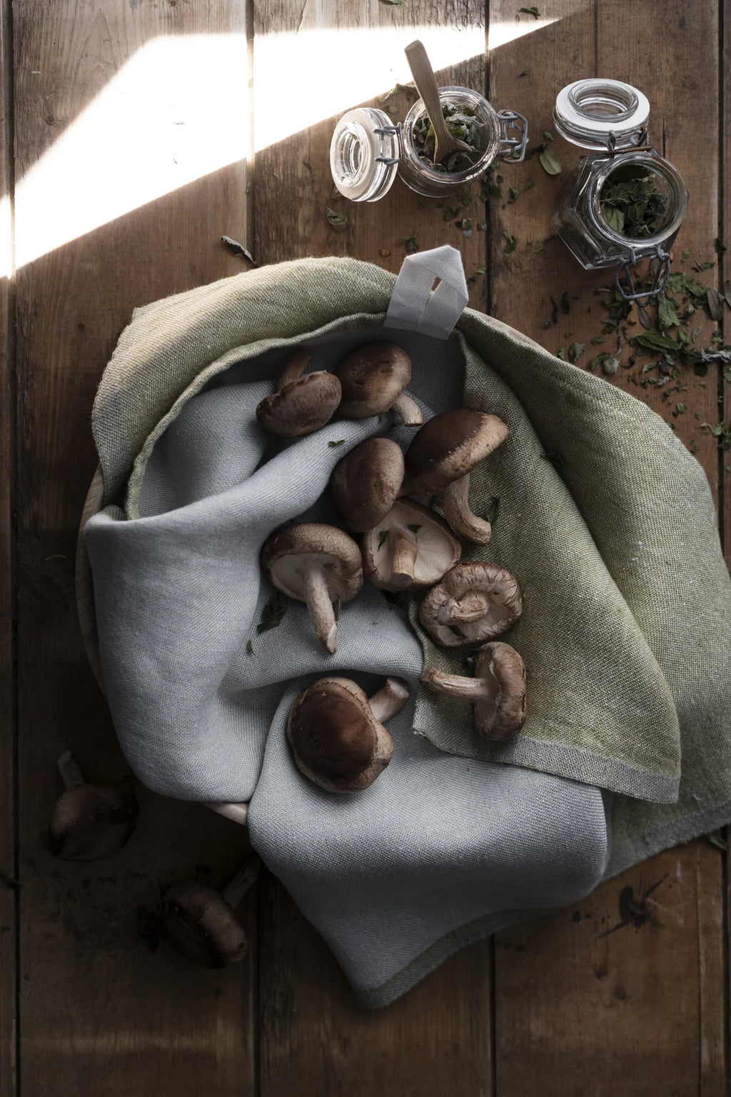 Green kitchen towel with mushrooms on top on a wooden table. 
