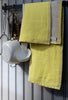 Yellow kitchen towel hanging on a rack with kitchen utensils by it's side. 