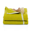 Folded green towel with a scrub brush on a white background