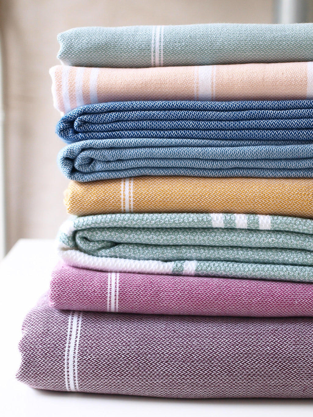 Stack of folded towels in various colors on a neutral background