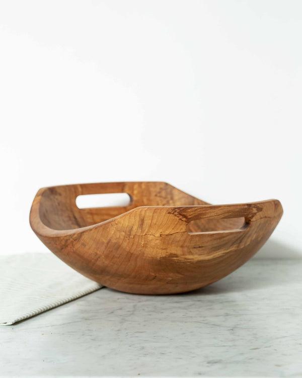 Wooden bowl with a handle on a light gray surface