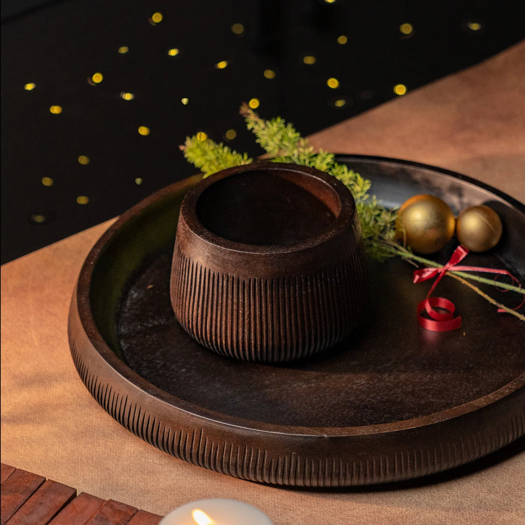 Wooden bowl on a wooden tray with decorative elements on a dark background