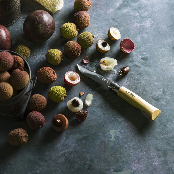 Lychees with a knife on a dark surface