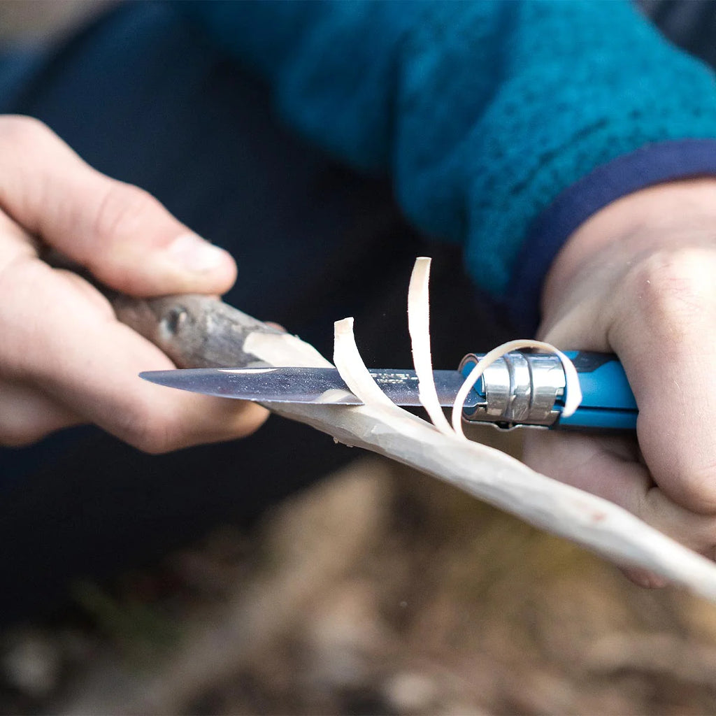 Person using a kids knife to cut stick with a blurred background