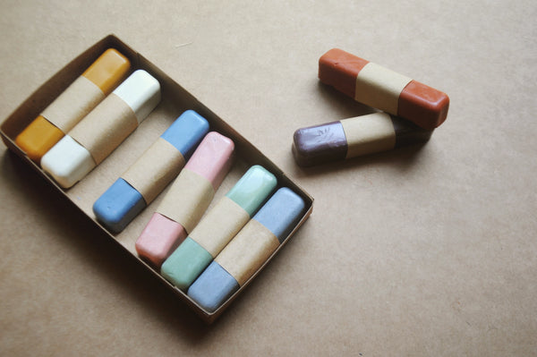 Set of colorful pastel crayons in a box on a beige surface