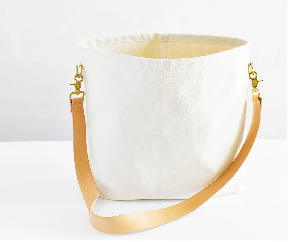White tote bag with a beige strap on a white background