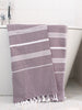 Purple towel with white stripes draped over a bathtub.