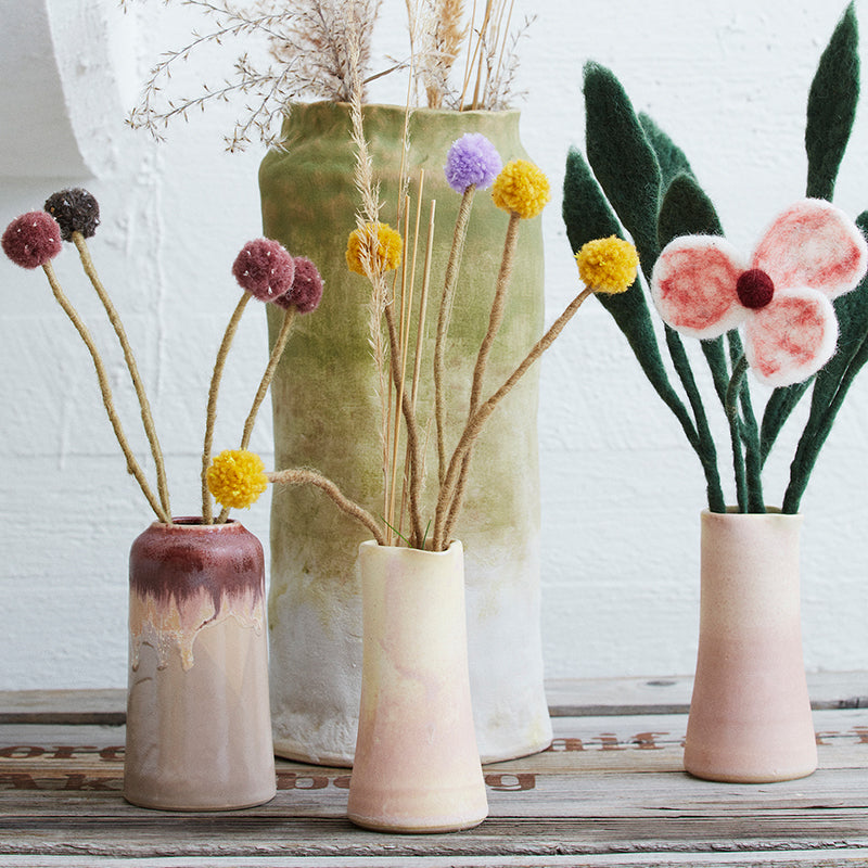 Set of ceramic vases with floral and decorative elements on a wooden surface.
