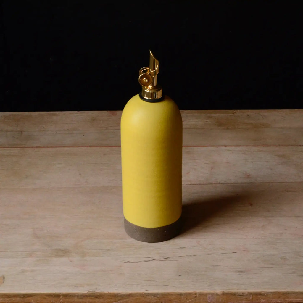 yellow ceramic oil bottle with gold cap on a wooden surface