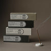 Stack of incense boxes with a smoking incense stick on a dark background