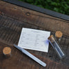 Notebook with a twizzer and small glass jars on a wooden surface